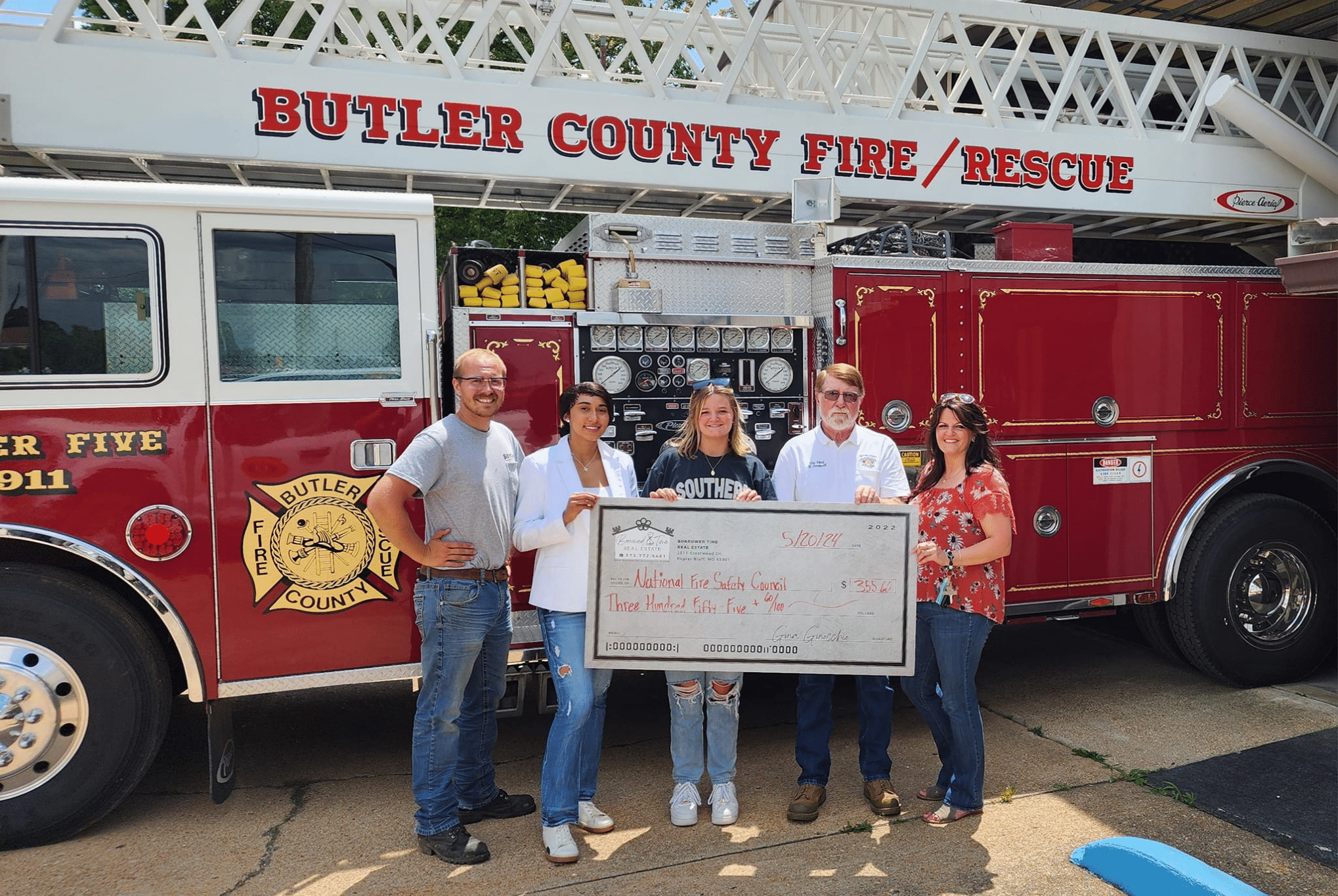 Borrowed Time Real Estate presents a community donation check with Butler County Fire & Rescue in front of a fire truck.