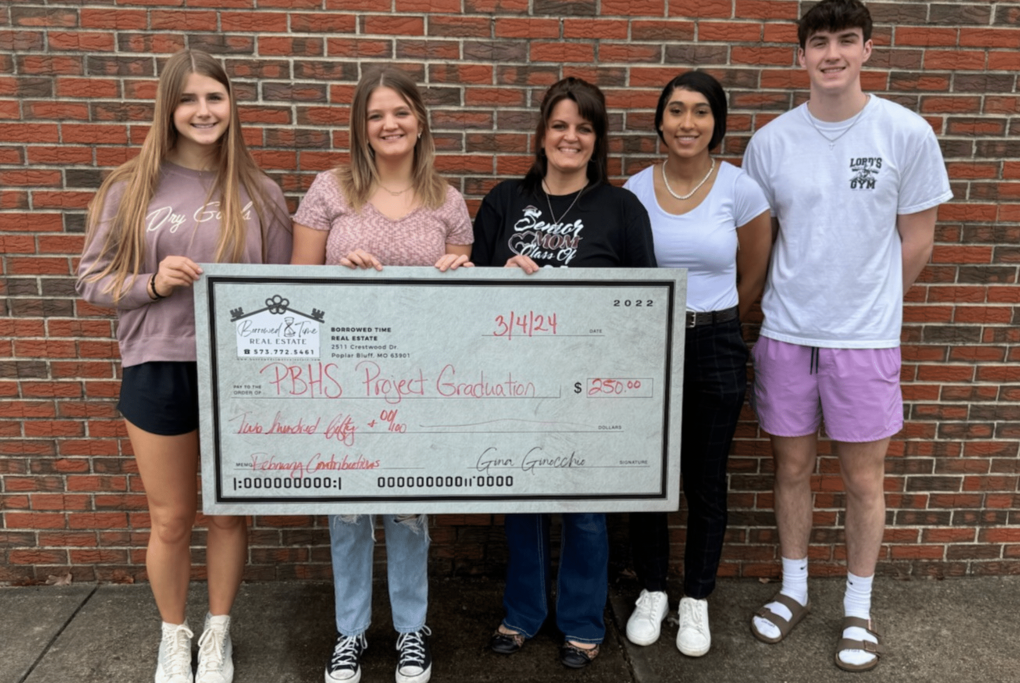 Borrowed Time Real Estate presents a donation check for PBHS Project Graduation with students and supporters.
