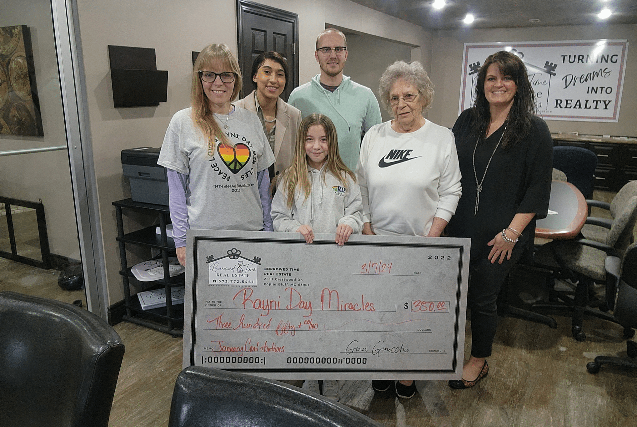 Borrowed Time Real Estate presents a community donation check to Rayni Day Miracles with local supporters.