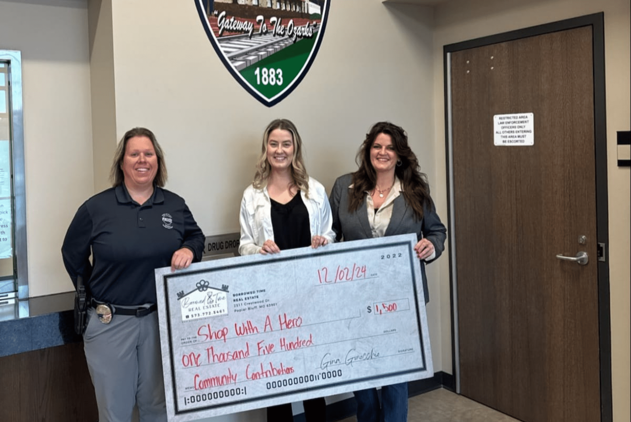 Borrowed Time Real Estate presents a Shop With A Hero community donation check at the Poplar Bluff Police Department.