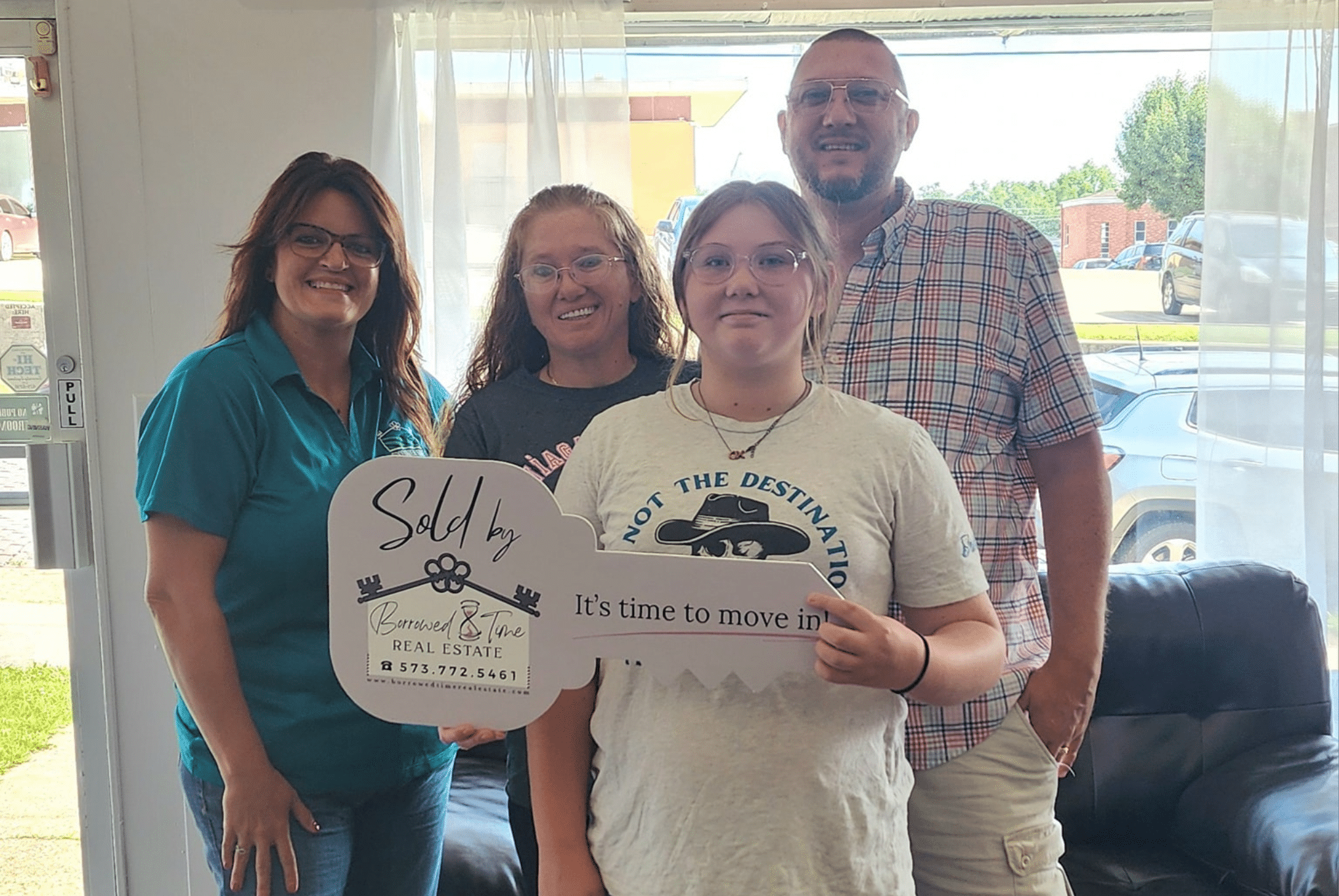 Homebuyers holding sold key sign after USDA loan closing with Borrowed Time Real Estate